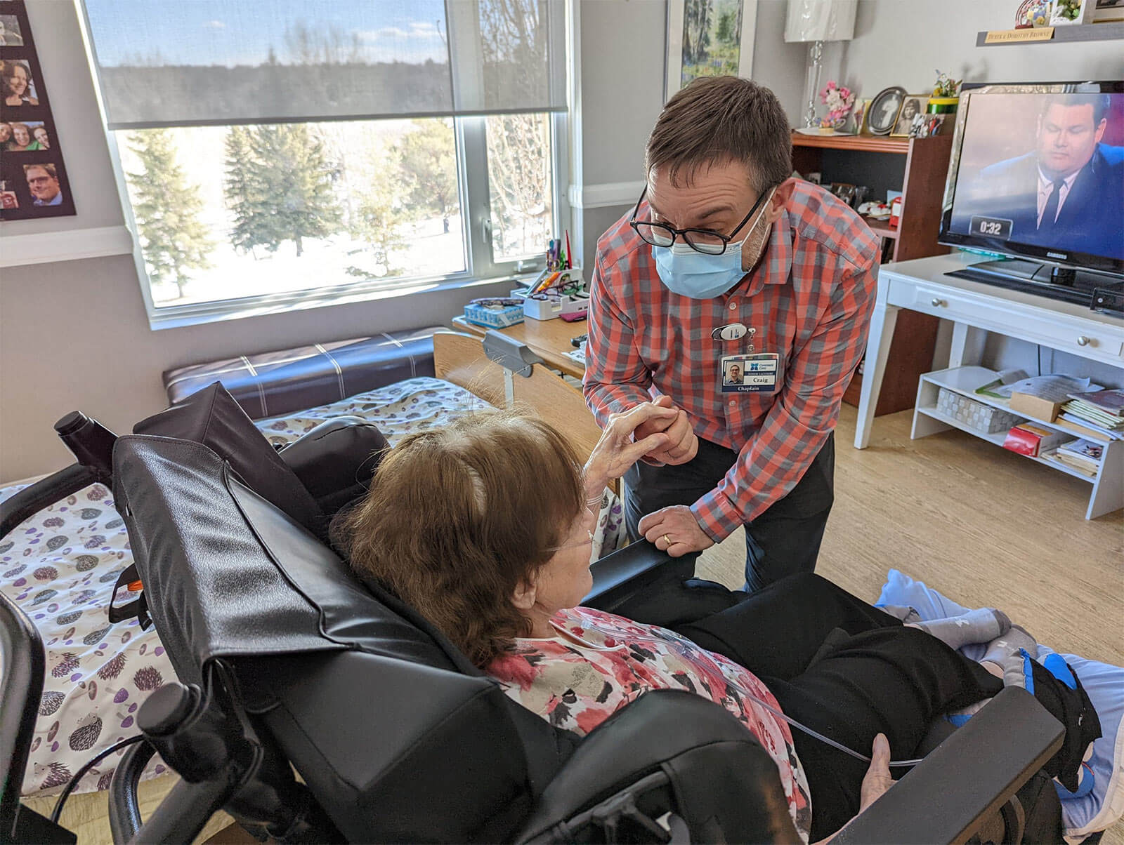 Craig Traynor holds the hand of and speaks to a resident who is seated in a wheelchair