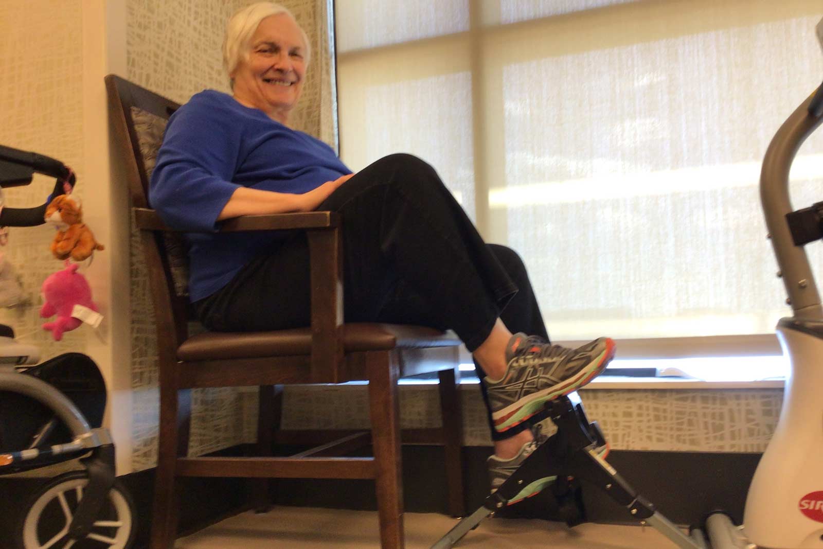 Senior woman pedaling an exercise bike by a window