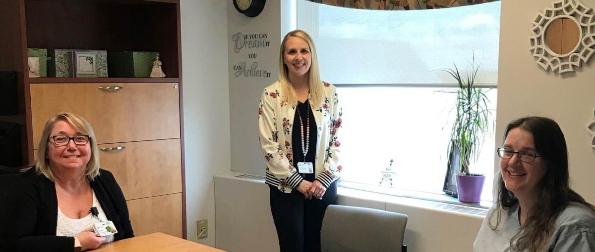 Three healthcare team members pose together in an office