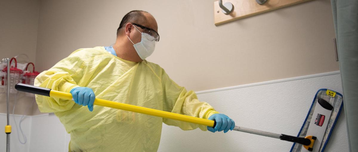 Housekeeping staff mops a wall in a hospital