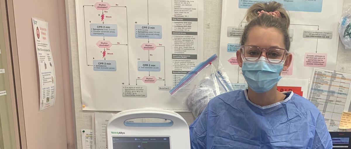 Tanya stands next to medical equipment in an exam room