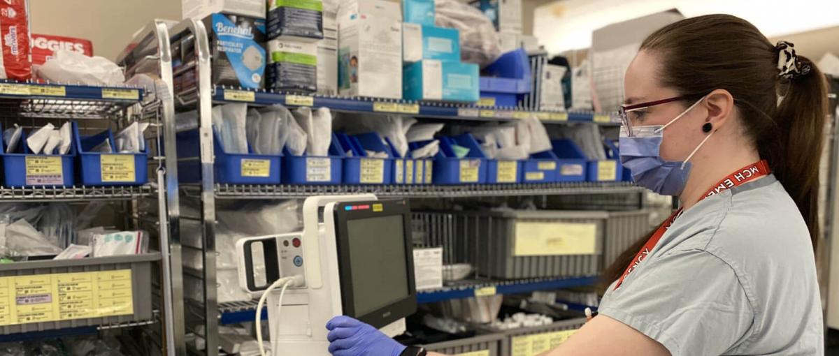 A licensed practical nurse looks into the screen of a heart rate monitor