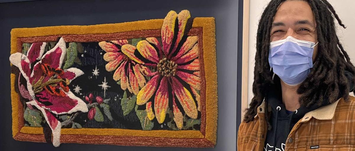 Edmonton artist AJA Louden poses beside his artwork depicting stargazer lilies and asters created from yarn
