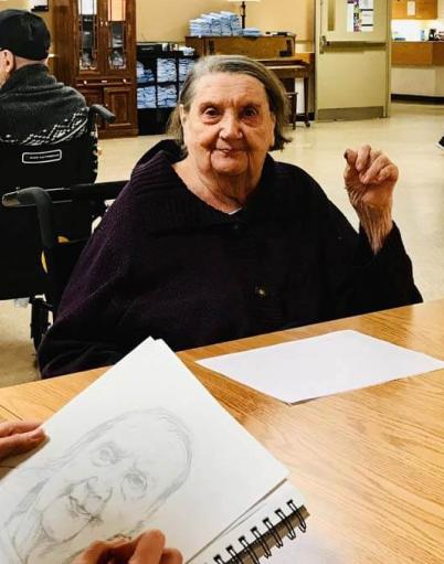 Resident Darlene Duff sits as recreation therapy assistant Jennie Vegt sketches her portrait