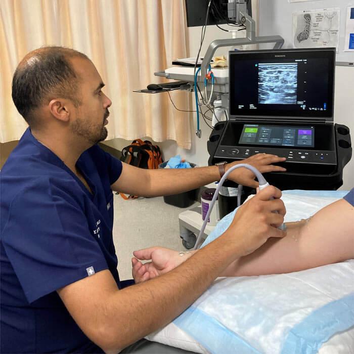 A doctor uses ultrasound vein mapping on a patient's arm to determine hemodialysis access for the patient