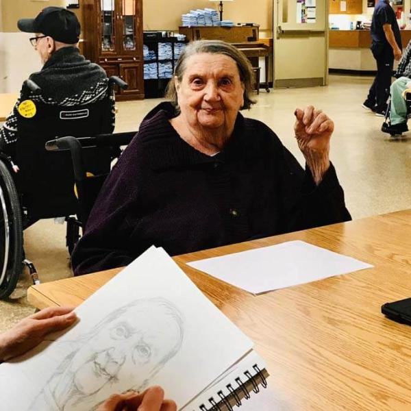 Resident Darlene Duff sits as recreation therapy assistant Jennie Vegt sketches her portrait