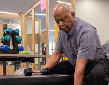 Man exercising with dumbbells while sitting on a bench in a fitness room